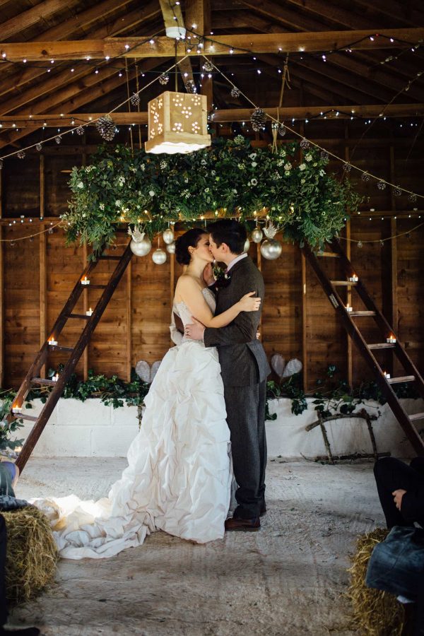 A photograph of newly wed kissing in a barn. The wedding theme rustic opulence