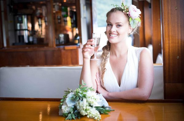 Bride drinking champagne on a boat by Verity Westcott Photography