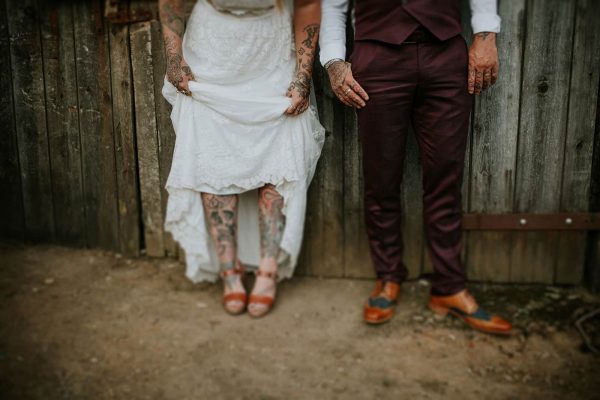 A photograph of the bride and groom but only their feet the bride is showing of her tattoos and the groom his shoes at their totally hipster festival wedding
