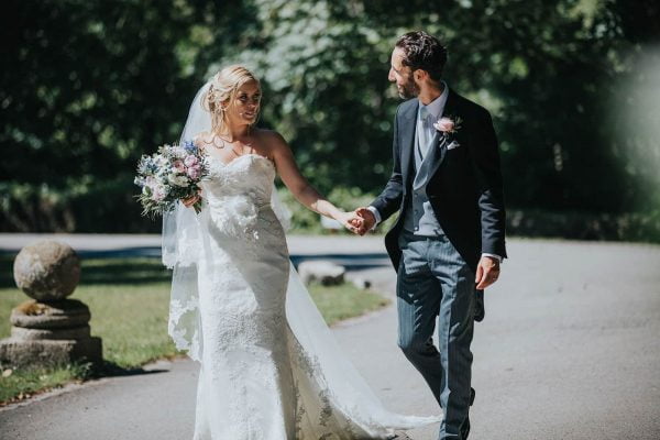 A photograph of newly weds walking hand in hand an English Country Garden Wedding