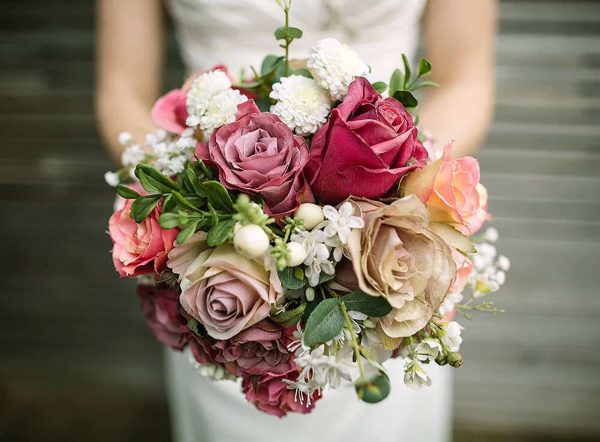 A photograph of a bride holding a bouquet of beautiful silk flowers