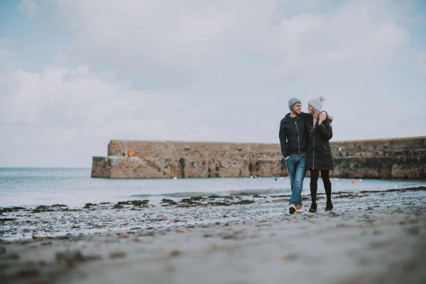 newly engaged couple walking along a beach