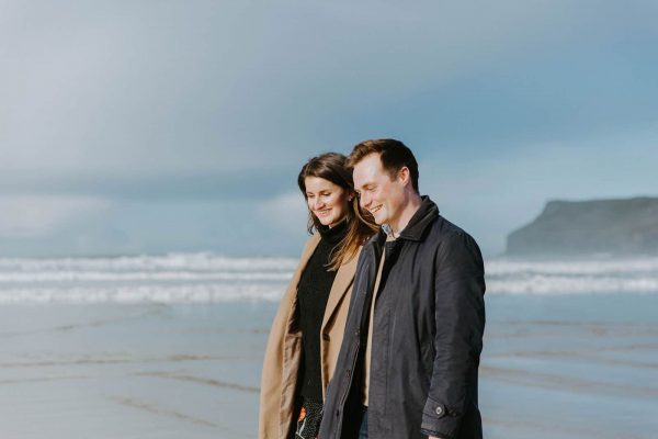 Alex and Piran's Engagement shoot with Wild Tide Weddings the couple are walking on a beach